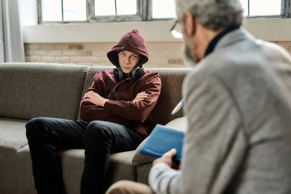 Rusteloze tiener jongen op de bank naast psychotherapeut — Stockfoto