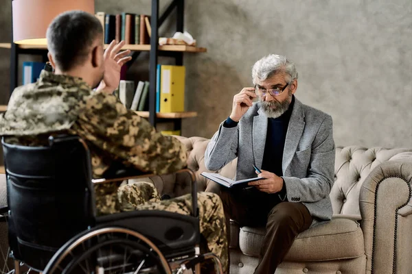 Psychotherapeut die luistert naar een militair in een rolstoel — Stockfoto