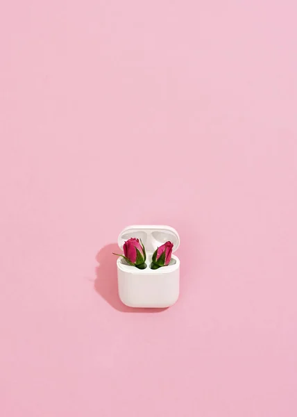 Perfect cadeau voor gadget liefhebbers. Oplader voor oortjes met twee roze rozen erin, verticaal schot — Stockfoto