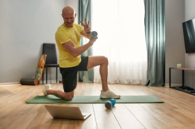 Antrenör dambıllarla antrenman yapıyor.