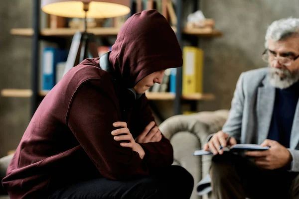 Depressieve tienerjongen zit in de buurt van psychotherapeut — Stockfoto