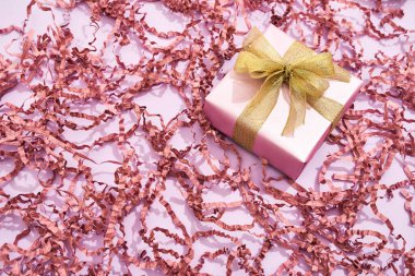 Kadınlar Günü için romantik bir hediye. Pembe arka planda, dekoratif pipetle süslenmiş küçük bir hediye kutusunun üst görüntüsü
