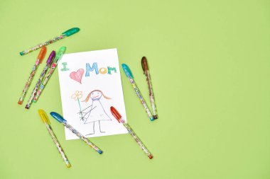 Dünyanın en iyi annesi için el yapımı tebrik kartı. Yeşil arka planda, anneler günü için renkli kalemlerle ya da kalemlerle renkli çocuk çizimlerinin en üst görüntüsü