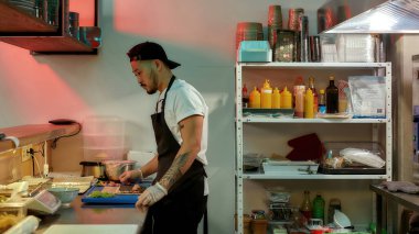 Profesyonel suşi şefinin, ticari mutfakta leziz dürümler yaparken Norveç çarşafının üzerine malzeme ekleyişinin yan görüntüsü