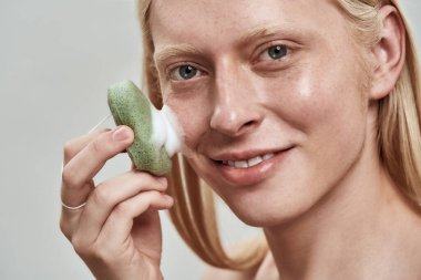 Yüz süngeri kullanan beyaz bir adamın portresi.