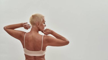 İç çamaşırlı olgun bir kadının arka planda yarı çıplak poz vermesi ve diğer tarafa bakması, mesaj için boşluk kopyalaması.