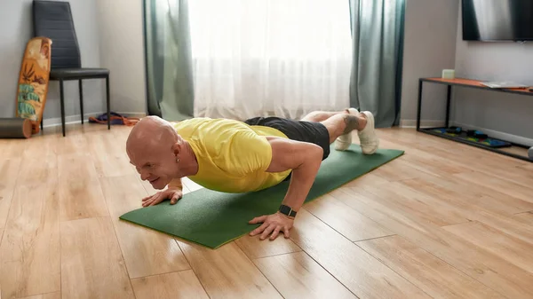 Fitt maradok. Felnőtt férfi fitness oktató sportruházat csinál push-up jóga szőnyeg otthon, edzés közben az önálló elszigeteltség — Stock Fotó