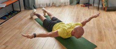 Kendini soyutlama sırasında çalışıyor. Evde yoga minderiyle spor giyinen olgun bir adam.