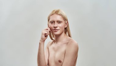 Gömleksiz beyaz çocuk yanağını sıkıyor.