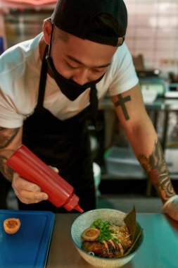 Erkek şef mutfakta çorba hazırlıyor.