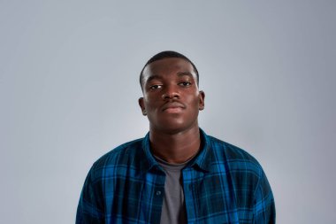 Sıradan gömlekli, kameraya bakan Afrikalı Amerikalı genç bir adamın portresi.