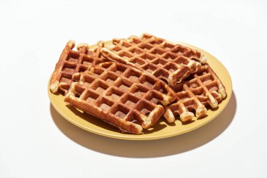 Ye beni. Taze pişmiş Belçika waffleları. Sarı tabakta şeker var. Arka planda izole edilmiş.