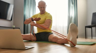 Spor adamı dizüstü bilgisayarla online egzersiz yapıyor.