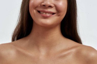 Doğal güzellik. Beyaz arka planda dururken kameraya gülümseyen sağlıklı ve temiz yüzlü genç ve güzel Asyalı bir kadının görüntüsü.