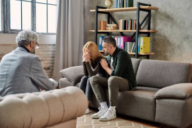 Genç kadın teselli eden kocanın yanında ağlıyor.