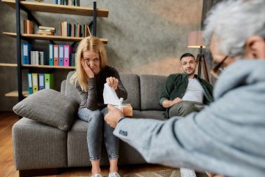 Ağlayan beyaz bir kadın kutudan peçete alıyor.