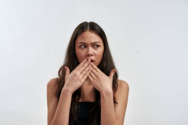Young surprised worried asian woman covering her mouth with two hands