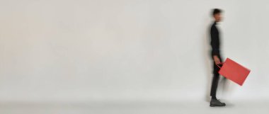 Blurred figure of man with red packet walking