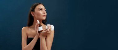 Genç kız makyajlı karanlık bir stüdyoda duruyor.