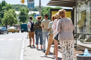 Maske takan, sırada bekleyen, otobüs durağındaki sosyal mesafeyi koruyan insanların tam boy görüntüsü. Coronavirus, pandemik konsept