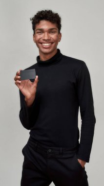 Mutlu genç Afrikalı Amerikalı adam elinde plastik kart tutuyor.