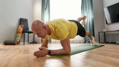 Tecrit sırasında egzersiz yapmak. Evde yoga minderinde bir kalas üzerinde spor giyim eğitmeni olarak antrenman yapıyorum.