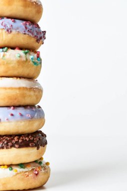 Etkileyici bir tatlı. Rengarenk donutların kulesi. Işık arkaplanı üzerine serpiştirilmiş şeker ve jöleli.