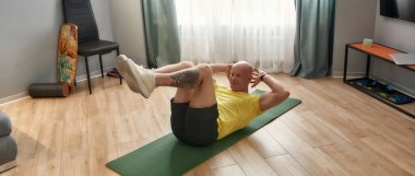 Spor salonunda spor yaparken spor salonunda mekik çeken kel bir adam.