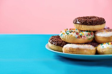 Meraklanma, mutlu ol. Mavi ve pembe arka plan üzerine serpiştirilmiş çeşitli renkli yuvarlak donutlar.