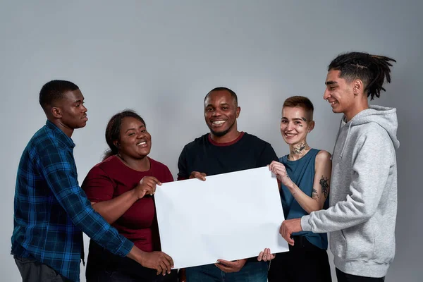 Cheerful young multiracial people holding banner mockup