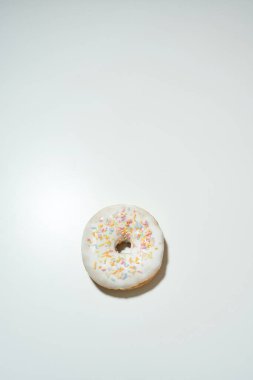 Çok şekerli. Dikey çekim lezzetli donut renkli serpiştirmeler ve beyaz şeker jölesi izole edilmiş açık arkaplan, metin için kopyalama alanı