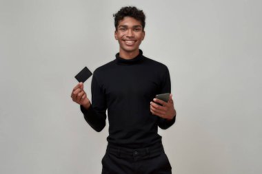 Young african american man with smartphone and card