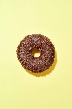 Şeker yemeyi bırak. Yeni pişmiş lezzetli çikolatalı çöreğin dikey çekimi sarı arka planda izole edilmiş parçacıklar.