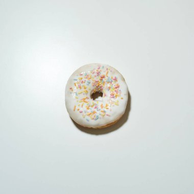 Taze pişmiş lezzetli bir çöreğin üst görüntüsü. Renkli serpiştirmeler ve beyaz şeker jöleli ve hafif arka planda izole edilmiş.