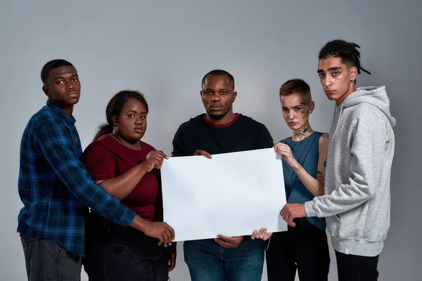 Sad multiracial people holding blank banner on light background