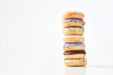 Donutlu kek. Rengarenk donutların kulesi. Işık arkaplanı üzerine serpiştirilmiş şeker ve jöleli.