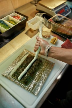 Erkek şef restoranda suşi pişiriyor.