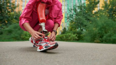Ayakkabı bağını bağlayan protez bacaklı engelli kişi