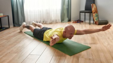 Fitness eğitimi. Evde yoga minderiyle spor giyinen olgun bir adam.