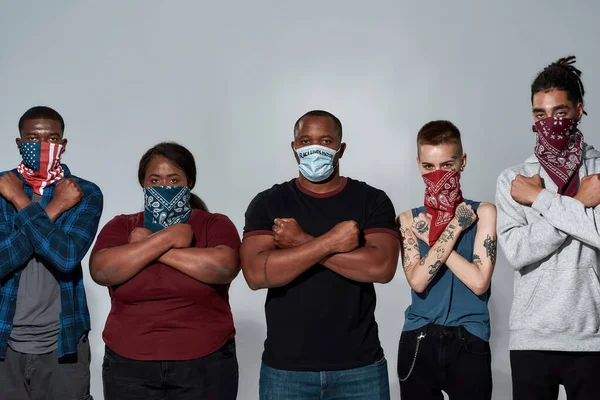 Young multiracial people in masks with crossed hands