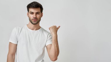 Tişörtlü bir adam başparmağıyla işaret ediyor.