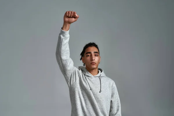 Young gypsy man with raised hand clenched in fist