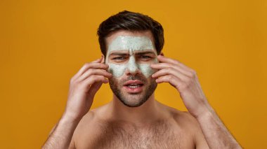 Yüzüne temizleyici yüz maskesi takan adam.