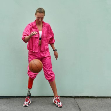 Spor elbiseli bir kadın basketbol topuyla oynuyor.