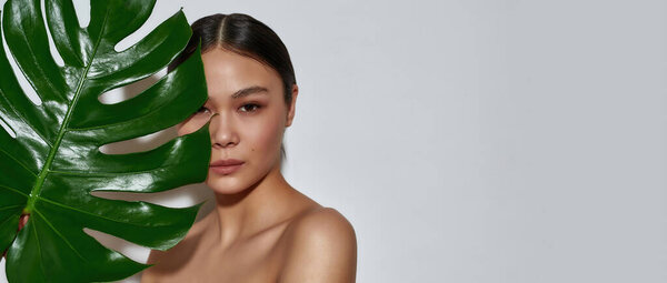 Портрет молодой красивой полуобнаженной азиатской девушки, волосы которой завязаны в хвостик