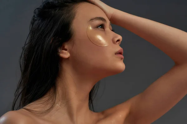 Jong mooi aziatisch half naakt vrouw met cosmetische oog patches kijken opzij — Stockfoto