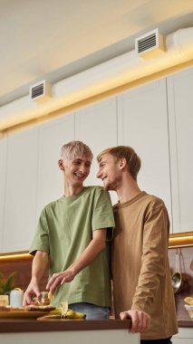 Gülümseyen eşcinsel çift sarılıyor ve gülüyor.