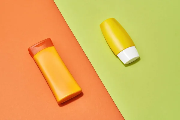 Tubos de plástico laranja e amarelo, garrafas com vitamina C natural produto de cuidados com o corpo isolado sobre fundo criativo laranja e verde — Fotografia de Stock