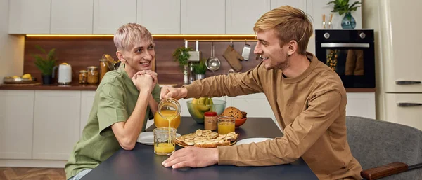Smiling young caucasian homosexual pair sitting at table — Stock Photo, Image
