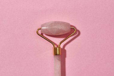 Gül kuvars düz yatar yüz masajı silindiri pembe arka planda izole